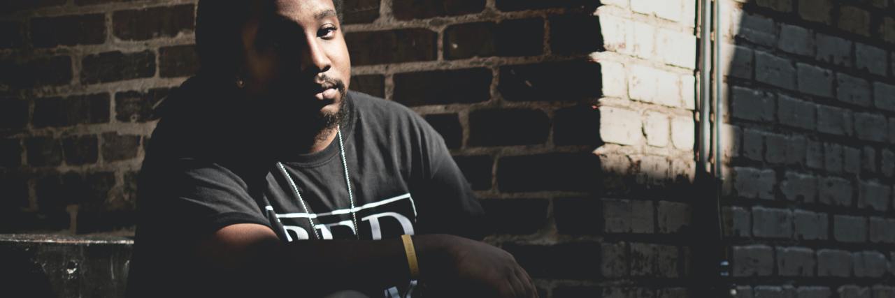 The Problem With Calling 911 on Black People in Mental Health Crisis photo of black man on street corner, looking into camera