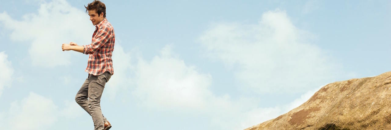 Treating Schizophrenia Through Medication and Lifestyle Changes Man standing on top of rocks with blue sky behind him