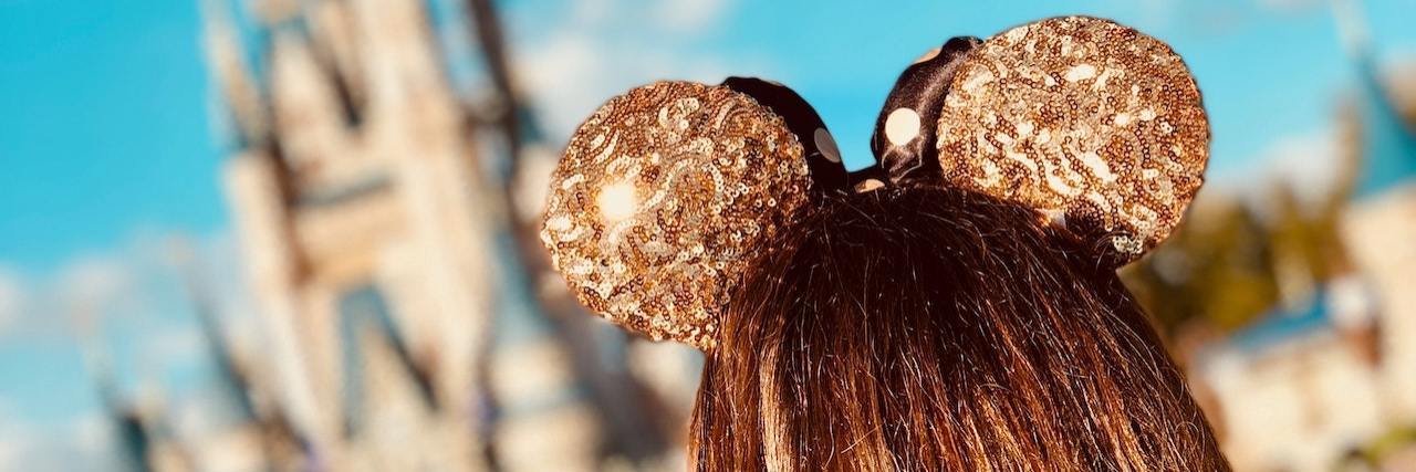 Disney Parks Win Lawsuit About Disability Accommodations Woman wearing Disney ears at Disney World in front of the castle