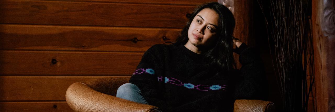 Victim-Blaming: I Was Almost Raped in My School Uniform photo of young woman sitting on leather chair by dark wood wall