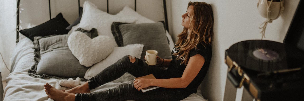 Woman sitting on her bed with cup of coffee