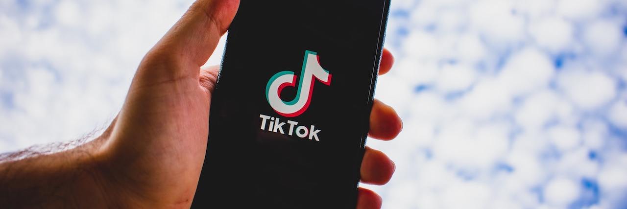 Hand holding a phone showing the TikTop app