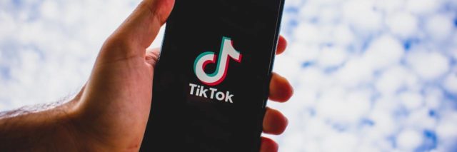 Hand holding a phone showing the TikTop app