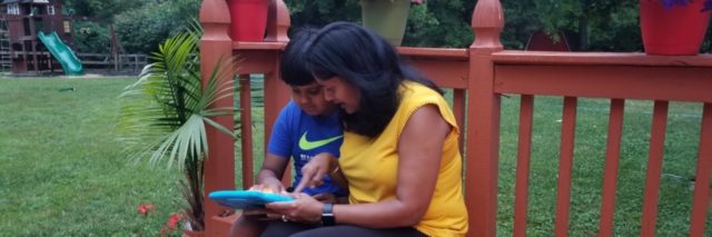 Tulika and her son using a tablet on the patio outside.