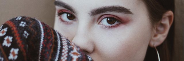 A woman in a sweater with pink eye makeup