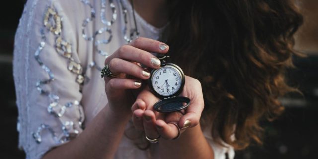 close up photo of a woman holding an open pocket watch