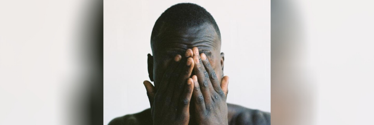 Black man with hands over his face