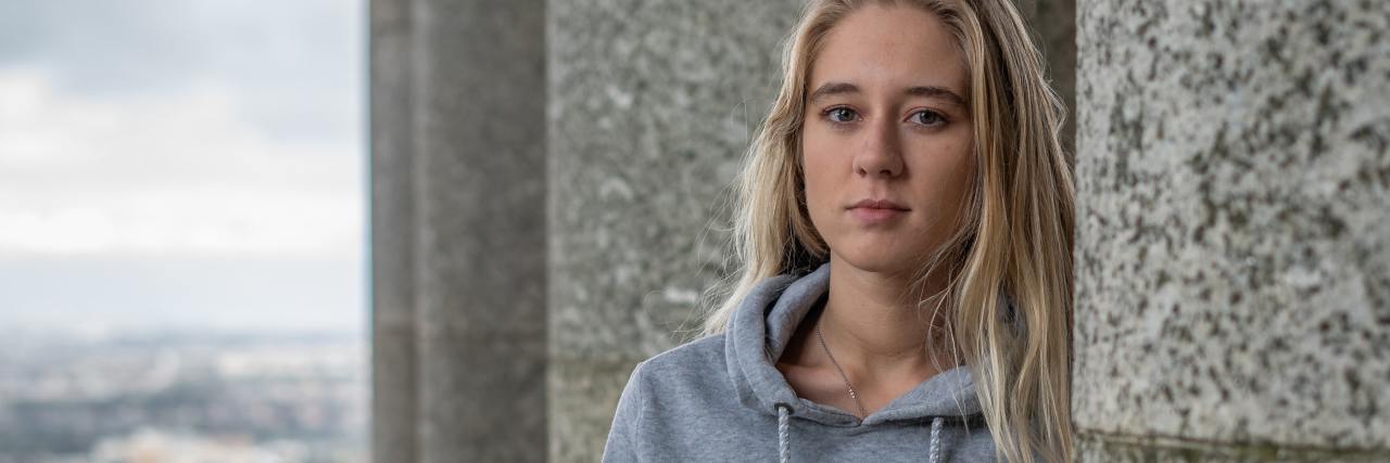 We Need to Help College Students With Treatment After Suicide Attempt photo of young blonde woman standing by stone pillars and looking into camera