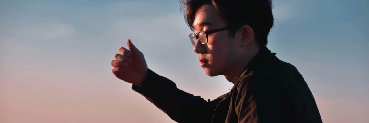 My Experience With Serious Side Effects to New Psychiatric Medication photo of young asian man wearing glasses, illuminated by sunlight