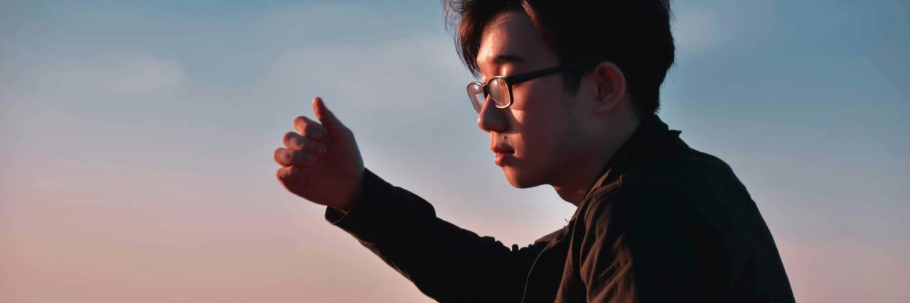 photo of young asian man wearing glasses, illuminated by sunlight