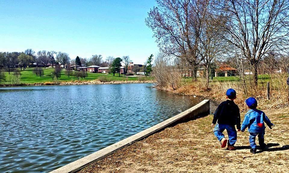 Neena's two boys walking hand in hand near a lake and trees