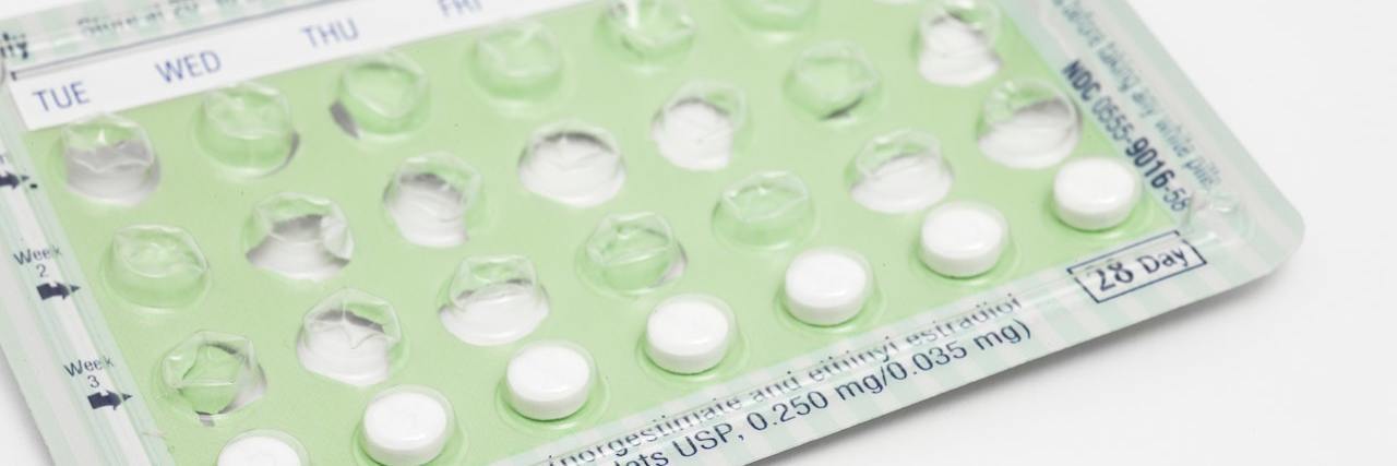 Half-finished pack of birth control pills with one pill on the table