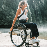 Woman in a manual wheelchair with forest in the background.