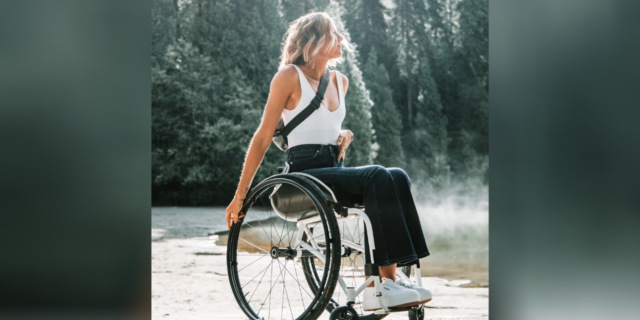 Woman in a manual wheelchair with forest in the background.
