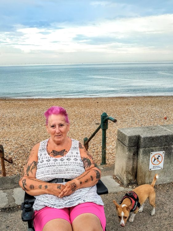 A woman with pink hair near a beach