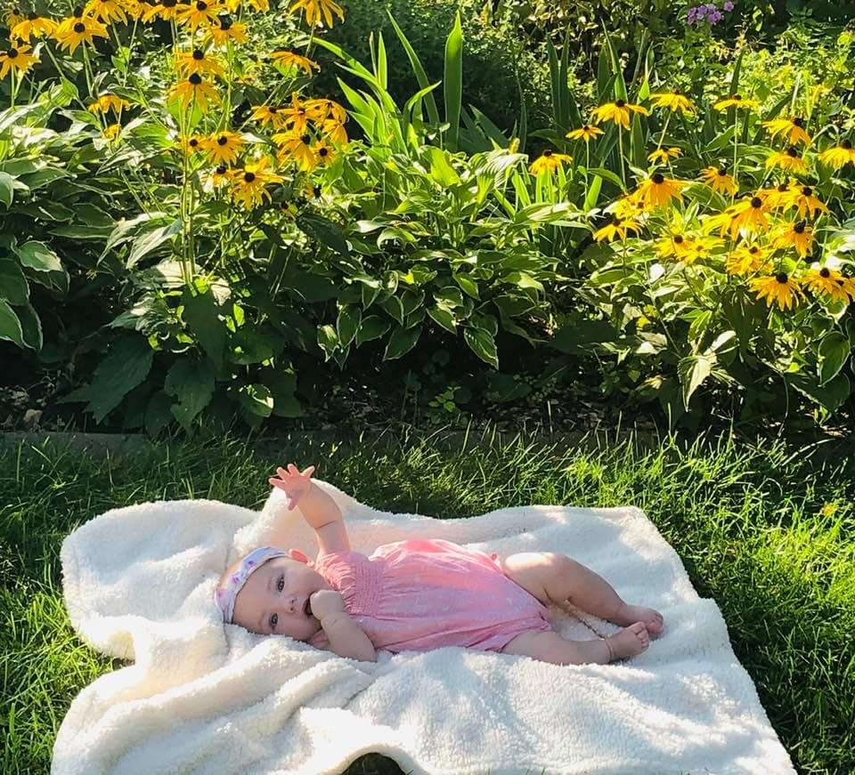 photo of contributor's daughter lying on blanket on grass in front of flowers