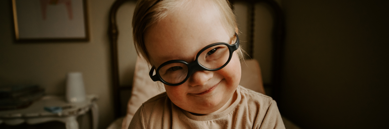 It's OK to Acknowledge Differences When We Talk About Disability Madison's son smiling. He has Down syndrome and wears black framed eyeglasses.