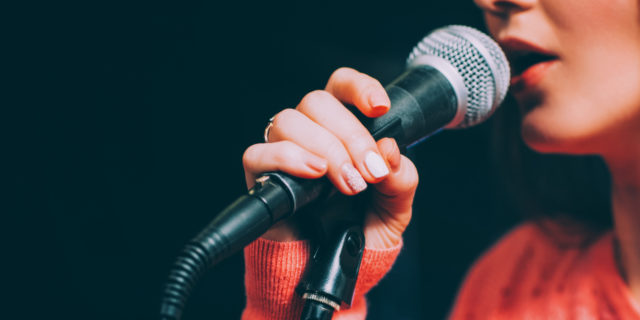 Woman singing and holding microphone.