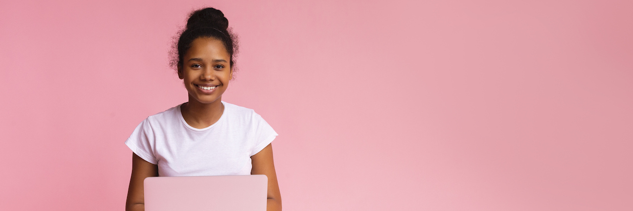 8 Back-to-School Mental Health Resources for BIPOC Students Student sitting cross-legged with an open laptop in her lap against a pink background
