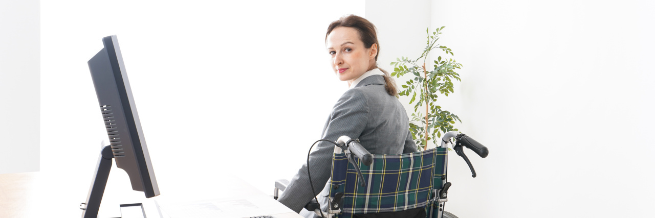 Young woman in a wheelchair working in office.