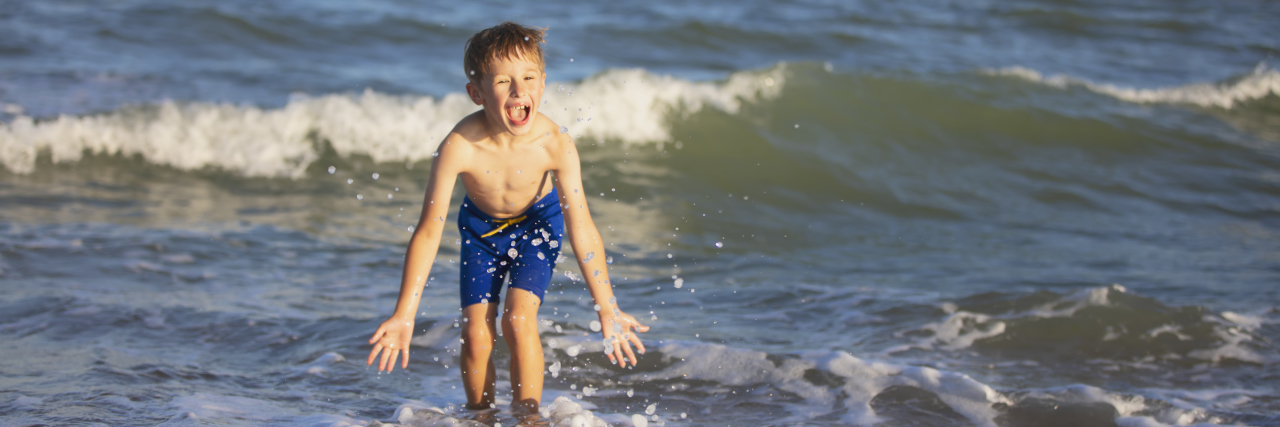 Tips for Vacations With a Child on the Autism Spectrum Boy playing in the ocean.