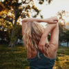 Blonde young woman stretching her hands in park
