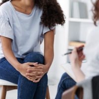 two people sitting across from each other in a therapy session, focus on lower halves of body