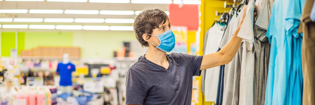 KHN: How Do You Know It’s OK to Go in Stores or Restaurants? Man in a clothing store in a medical mask because of a coronavirus.