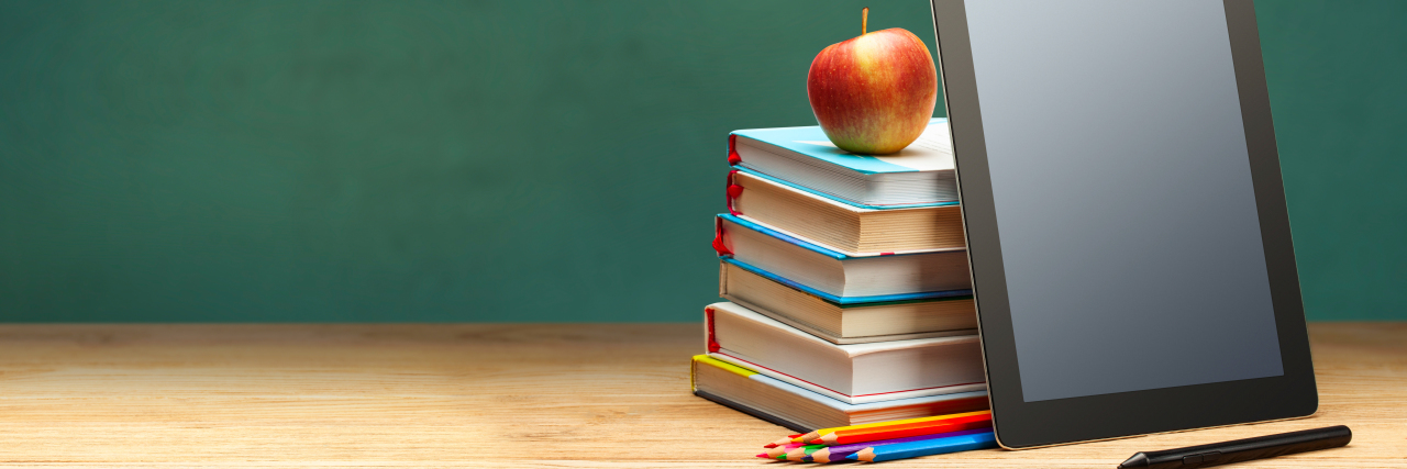 Virtual Education Guide for Disabled Students During COVID-19 Online education. Books and tablet with chalkboard in background.