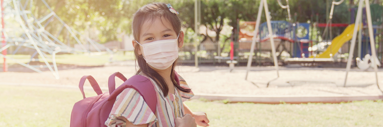 Where Are Kids With Disabilities in COVID-19 School Plans? Asian girl wearing mask and carrying schoolbag with hand sanitizer.