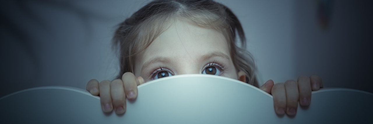 15 Things Anxious Kids Did That Seemed 'Weird' a little girl peaking from behind a bed