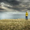 Woman standing under dark clouds looking out over a body of water