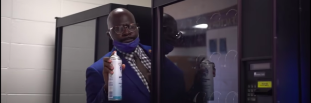 Dr. Quentin J. Lee peeks out from behind a school vending machine ready to spray a can of Lysol