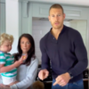 Laura, a woman with long brown hair, holds son Freddie, a young boy with curly blonde hair, next to Tom Hopper, a tall man with short hair