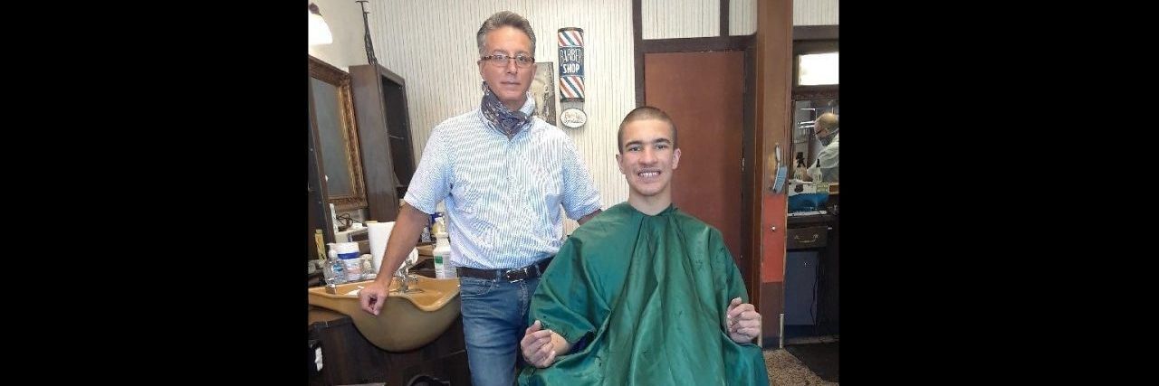 The Anniversary of My Son With Autism's Haircut is Worth Celebrating A young man is sitting in his barber's chair
