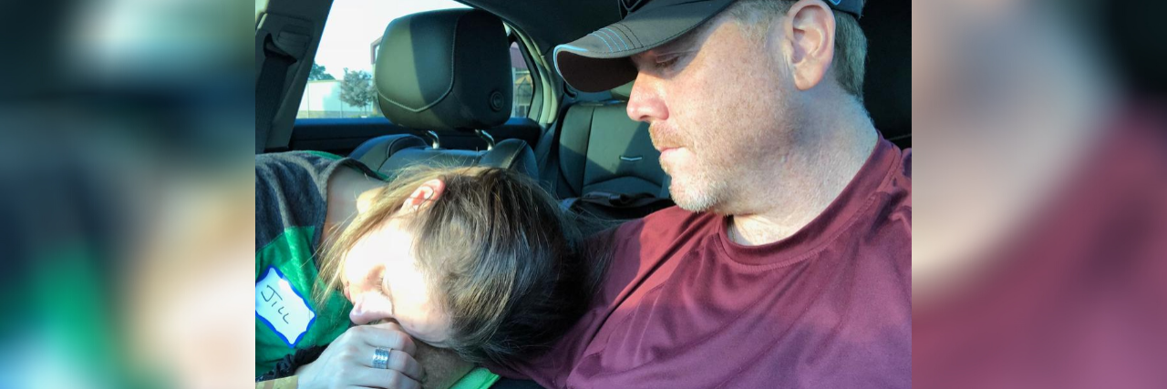 Accepting My Partner Is My Caregiver for My Mental Illness photo of the contributor and her partner, as she lies her head on his arm in a car
