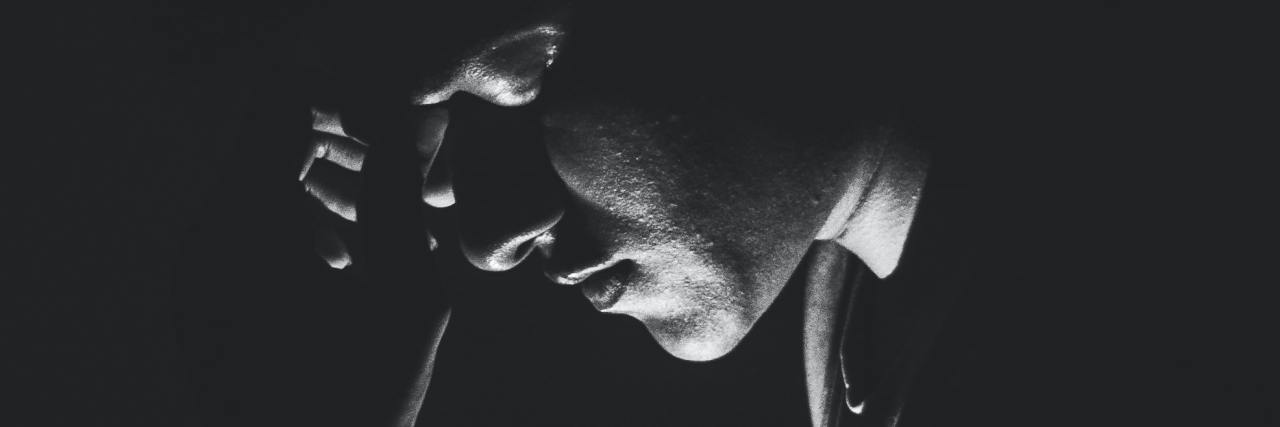 photo of man in black and white, standing in darkness illuminated from below