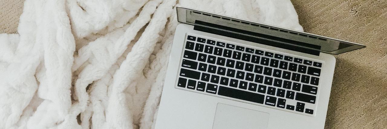 7 Legit Work-from-Home Jobs for People With a Disability An open laptop on a fluffy white blanket on the floor