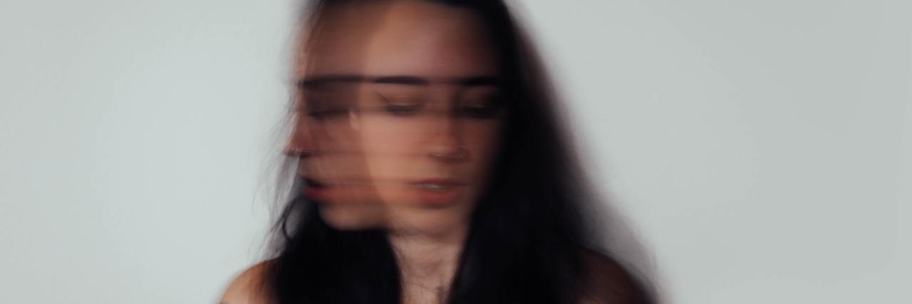photo of a young woman with a blurred face as she shakes her head over a long exposure