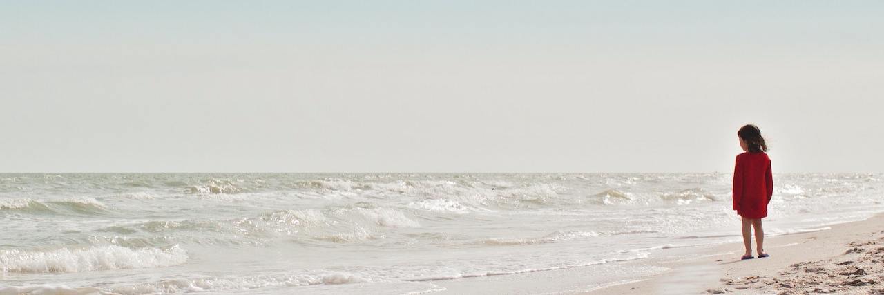 Challenging the Narrative of Fault and Blame After Childhood Abuse Young girl standing on beach alone looking out over water