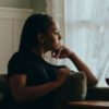 photo of Black woman looking out of window in thoughtful pose