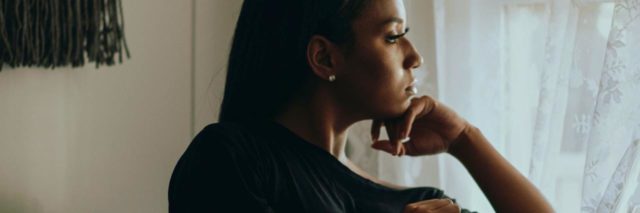 photo of Black woman looking out of window in thoughtful pose