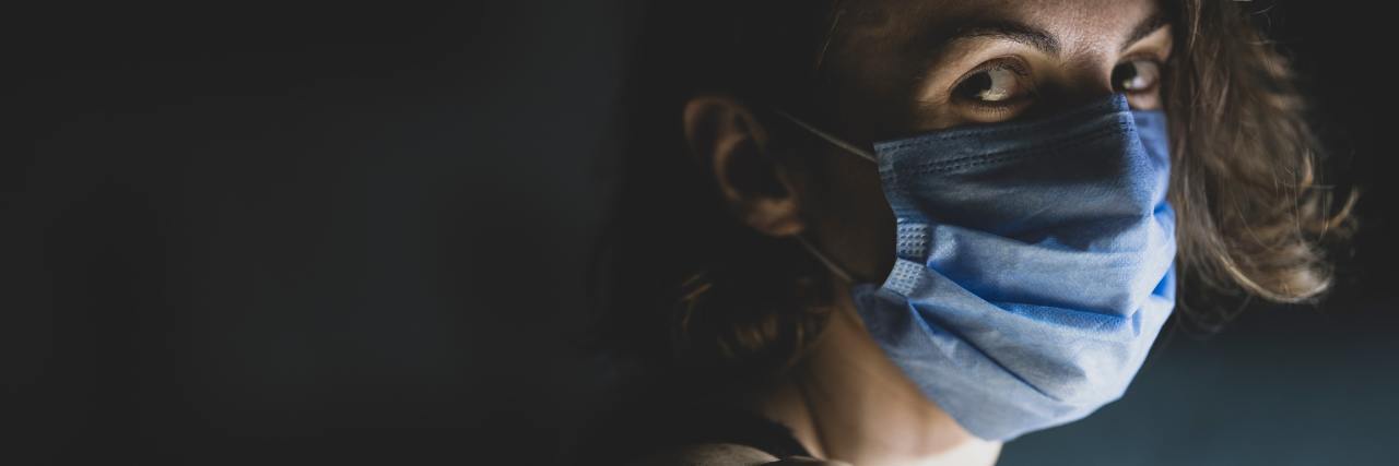 How Responses To COVID-19 Are Similar To Depression and Anxiety photo of woman with scared expression, looking into camera from side view while wearing a face mask