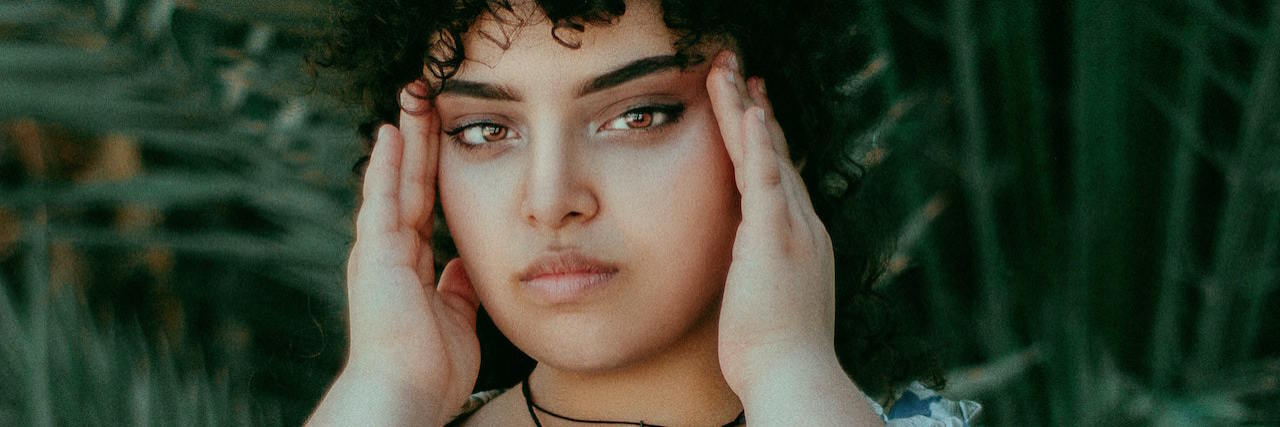 4 Types of Harmful Fatphobia in ED Treatment Centers A woman holding her head in between her hands