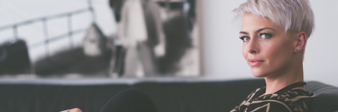 Why You Should Do the Things You Avoid Because of Mental Illness photo of woman sitting on sofa and looking into camera with intense expression