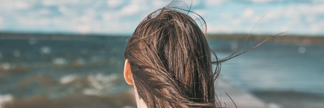 Recovery Is Not About Returning to the Person You Used to Be Woman facing a bright, stormy sea