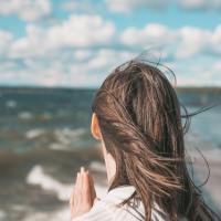 Woman facing a bright, stormy sea