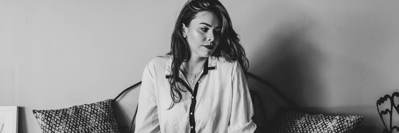 Depression Makes Me 'Standoffish' To My Husband black and white photo of woman sitting on a couch looking away