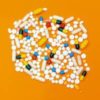 Photo of different medications/pills together to form a circle, on an orange background