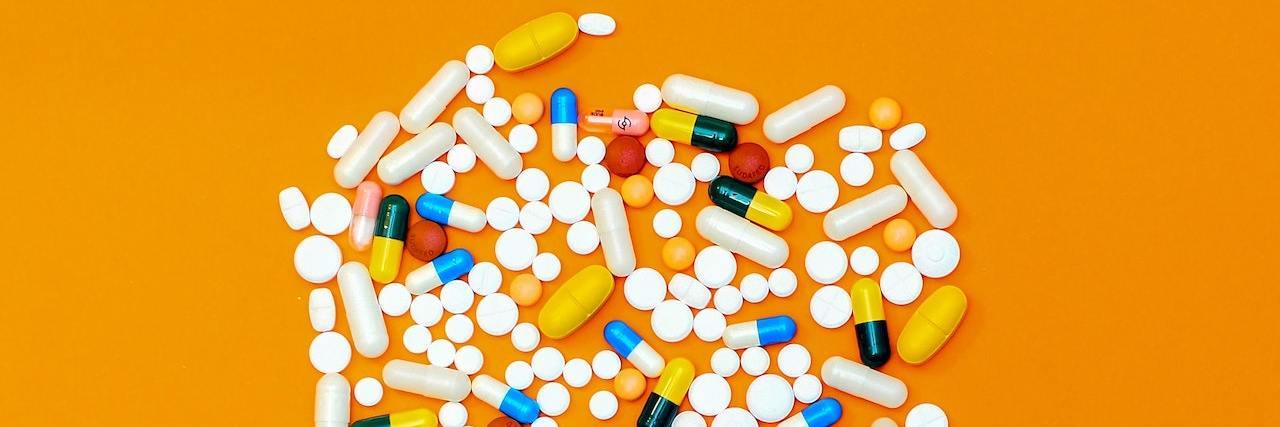 Photo of different medications/pills together to form a circle, on an orange background